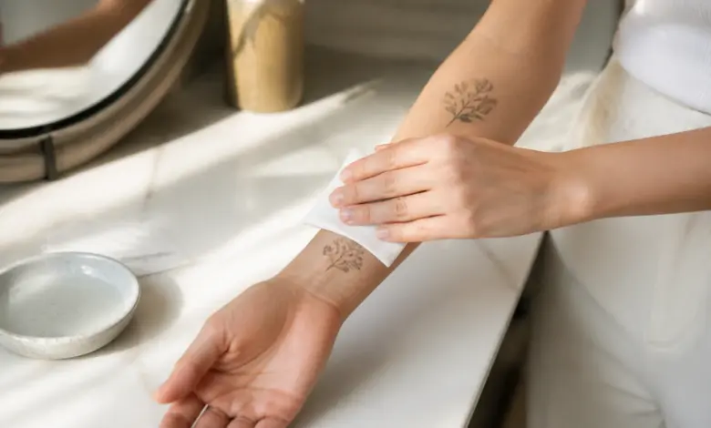 Temporäre Tattoos: Haltbarkeit, Arten und Risiken 5 Temporäres botanisches Tattoo wird mit einem feuchten Tuch auf den Unterarm übertragen