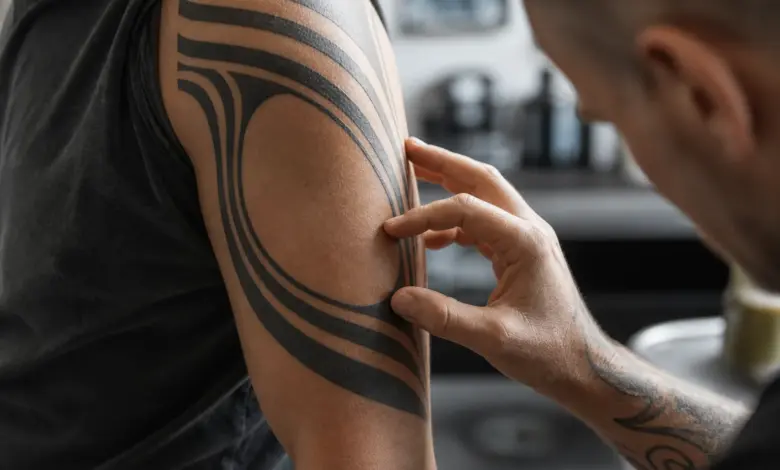 Tribal Tattoo: Bedeutung und Vorlagen mit Symbolik 13 Verheiltes schwarzes Tattoo aus breiten geometrischen Linien am Oberarm