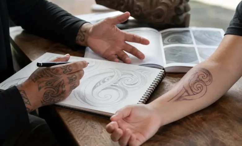 Maori Tattoo: Bedeutung und Symbolik der traditionellen Körperkunst 14 Tattoo-Beratung mit fließenden Spiralzeichnungen in einem Skizzenbuch